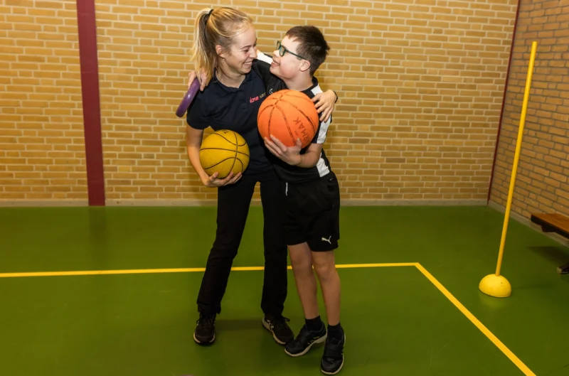 Cliënt speelt samen met bewegingstherapeut een potje basketbal bij Move it for Kidzz
