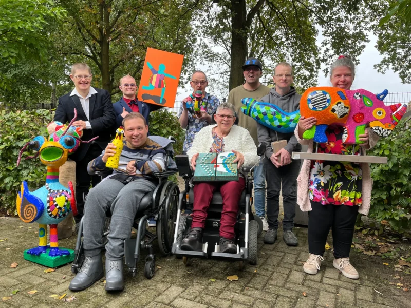Groep cliënten van ArtORO someren die kunstwerken hebben gemaakt.